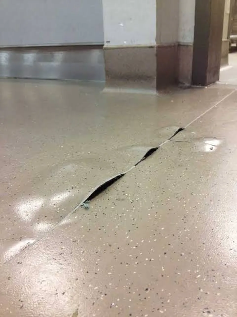 התקלפות ציפוי אפוקסי בקו ליד עמוד ופתח — הציפוי מתרומם ונסדק